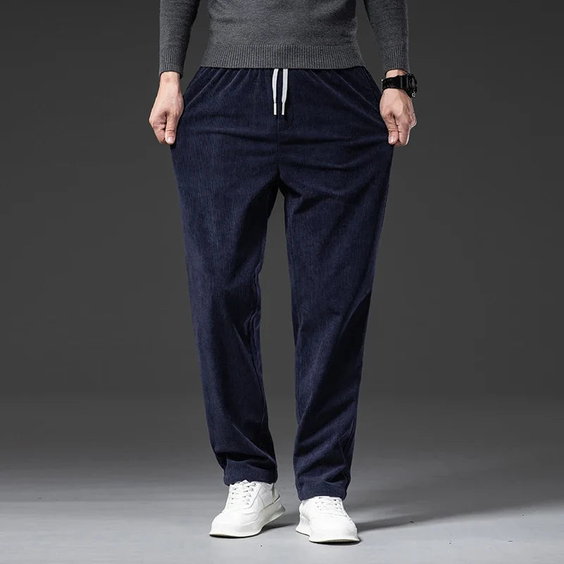 Man wearing navy blue corduroy drawstring pants with a straight leg, front view