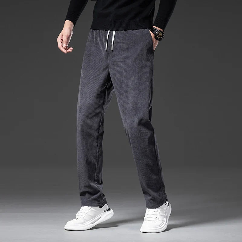 Man wearing gray corduroy drawstring pants with a straight leg, side view