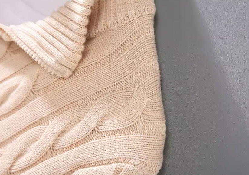 Close-up of the cable knit shoulder and ribbed collar on a men's beige sweater